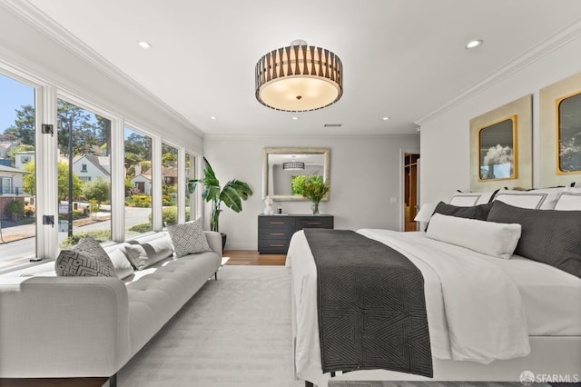 bedroom featuring ornamental molding, light hardwood / wood-style floors, and a walk in closet