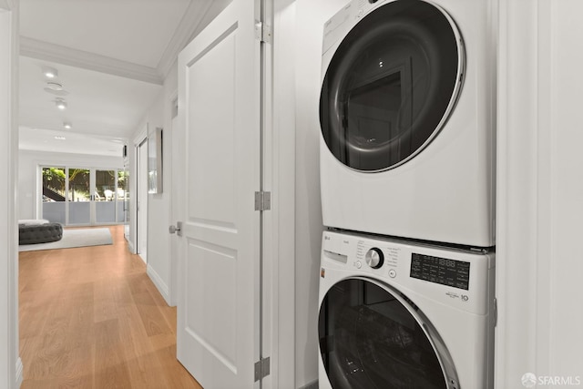 clothes washing area with stacked washer / dryer, crown molding, and light hardwood / wood-style flooring