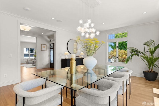 dining space with ornamental molding, light hardwood / wood-style floors, and a healthy amount of sunlight