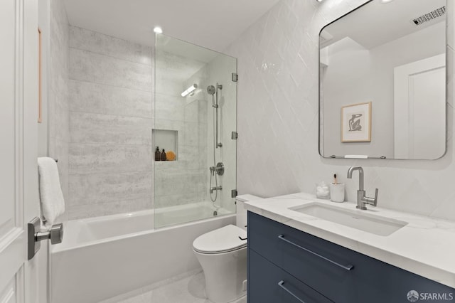 full bathroom with vanity, backsplash, bath / shower combo with glass door, tile walls, and toilet