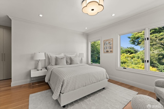 bedroom featuring ornamental molding and light hardwood / wood-style flooring