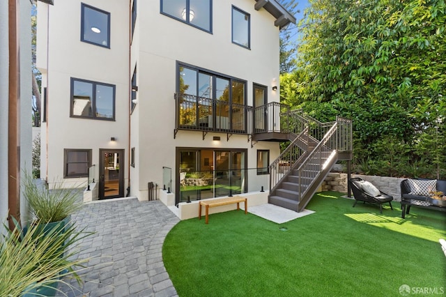 back of property with a balcony, a patio area, and a yard