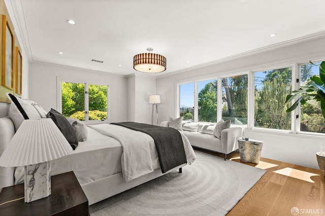 bedroom featuring multiple windows, crown molding, and hardwood / wood-style floors