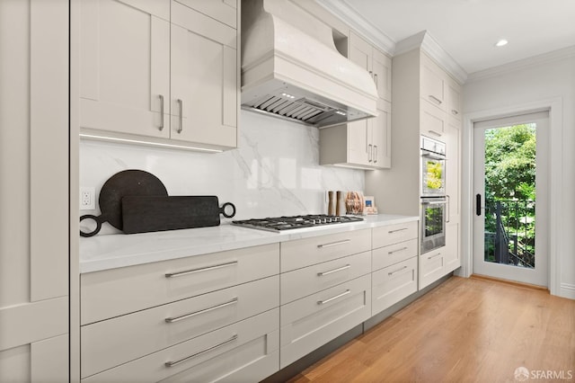 kitchen featuring white cabinets, premium range hood, stainless steel appliances, and light hardwood / wood-style floors