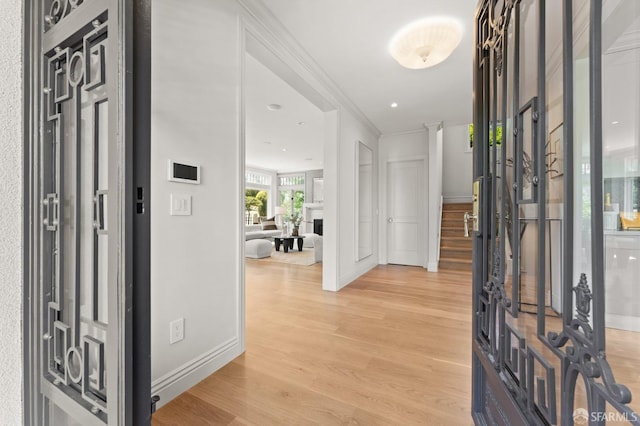 entryway with light wood-type flooring, decorative columns, and ornamental molding