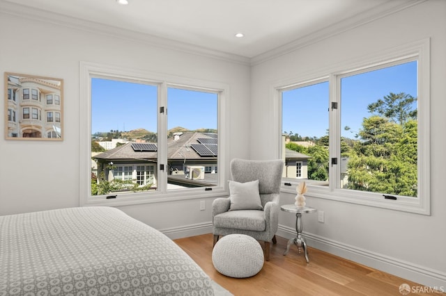 bedroom featuring light hardwood / wood-style flooring, crown molding, and multiple windows