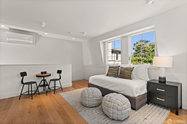 bedroom with light hardwood / wood-style flooring and a wall mounted air conditioner