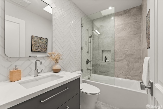 full bathroom with tile walls, backsplash, vanity, tiled shower / bath, and toilet