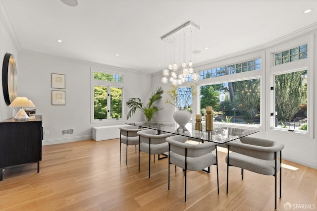 dining room featuring ornamental molding, light hardwood / wood-style floors, and a notable chandelier