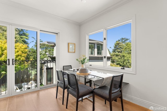 dining space with ornamental molding and light hardwood / wood-style floors