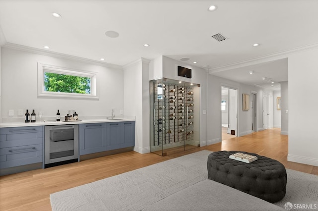 bar featuring wine cooler, ornamental molding, sink, gray cabinets, and light wood-type flooring