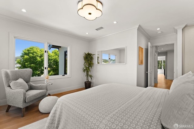 bedroom featuring crown molding, hardwood / wood-style floors, and ornate columns