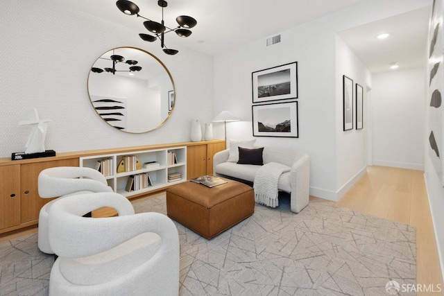 living room with light hardwood / wood-style floors and an inviting chandelier