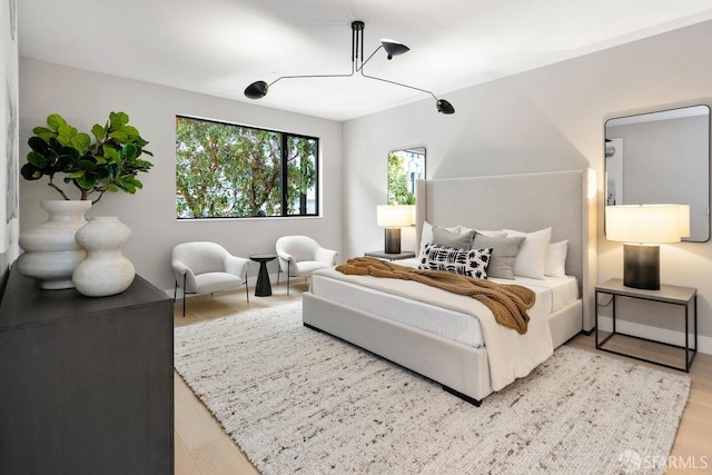 bedroom featuring an inviting chandelier and light wood-type flooring