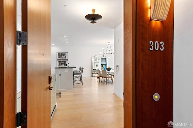 hall featuring light hardwood / wood-style flooring and a notable chandelier