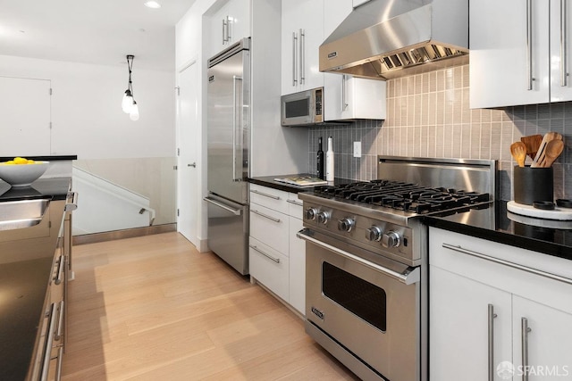 kitchen featuring wall chimney exhaust hood, high end appliances, and white cabinets