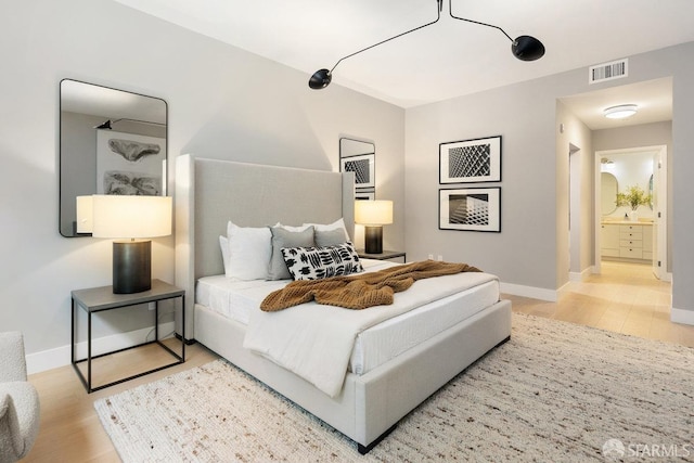 bedroom featuring ensuite bath and light hardwood / wood-style floors