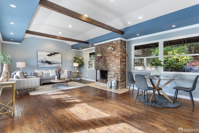 living room featuring hardwood / wood-style floors, beam ceiling, a fireplace, and ornamental molding