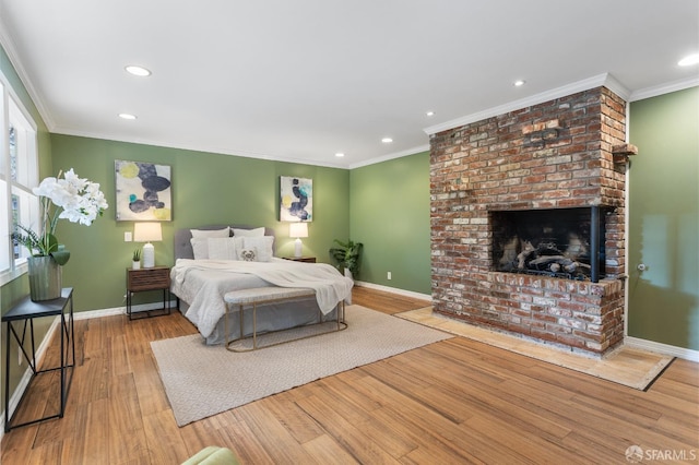 bedroom with crown molding, a brick fireplace, and light wood-type flooring