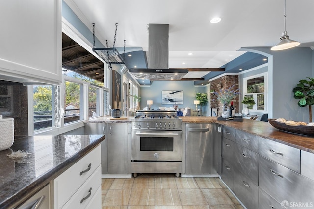 kitchen featuring island range hood, white cabinetry, dark stone counters, hanging light fixtures, and stainless steel appliances