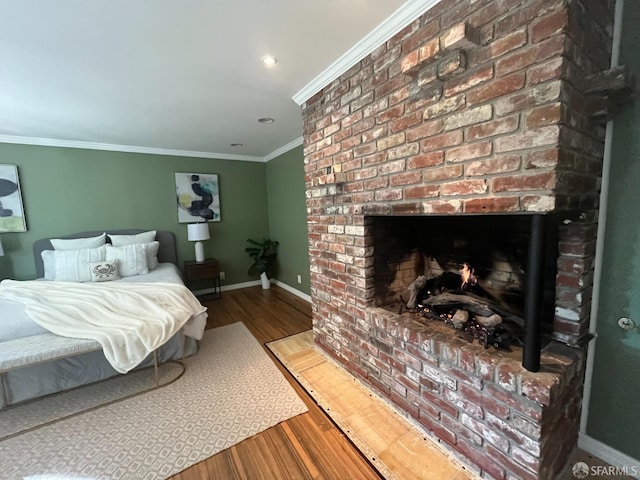 bedroom with wood-type flooring, a brick fireplace, and crown molding