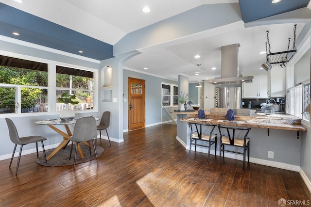 kitchen with stainless steel refrigerator, white cabinets, a kitchen bar, island exhaust hood, and kitchen peninsula