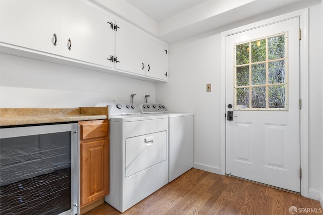 washroom with wine cooler, cabinets, light hardwood / wood-style floors, and washing machine and dryer