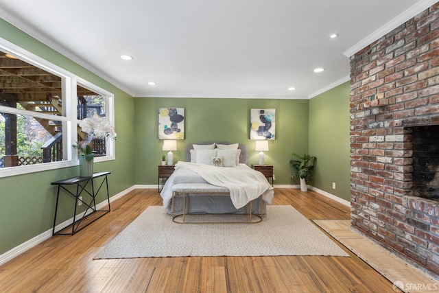 bedroom featuring ornamental molding, a fireplace, and light hardwood / wood-style floors