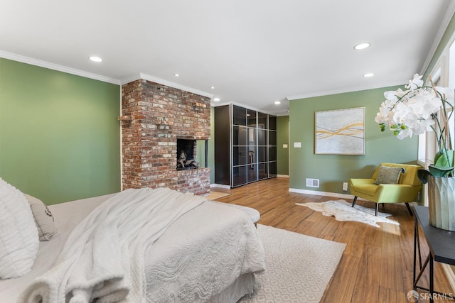 bedroom featuring wood-type flooring, a fireplace, and crown molding