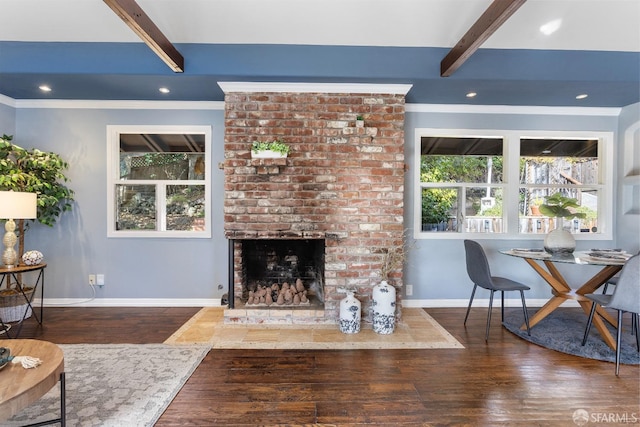 living room with beamed ceiling, crown molding, a brick fireplace, and dark hardwood / wood-style floors