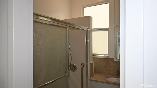 full bathroom featuring vanity, a shower with door, and backsplash
