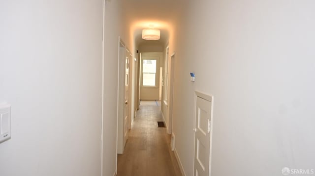 hall featuring light wood-style floors, baseboards, and visible vents