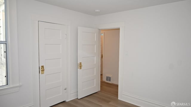 unfurnished bedroom with visible vents, baseboards, and wood finished floors