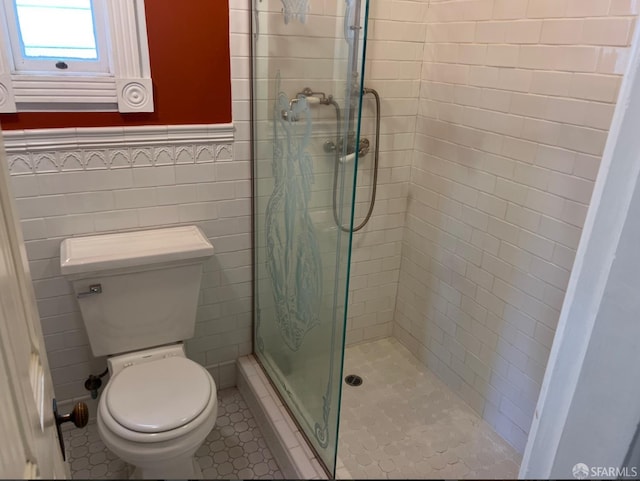 bathroom with tile walls, a shower with shower door, and toilet