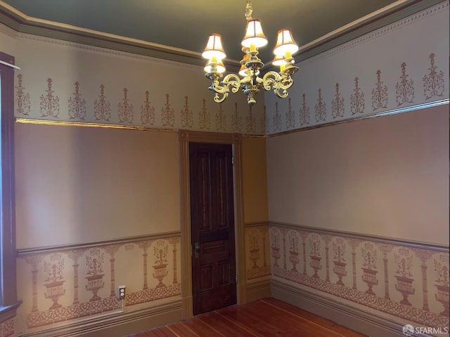 spare room with hardwood / wood-style floors, a notable chandelier, and ornamental molding