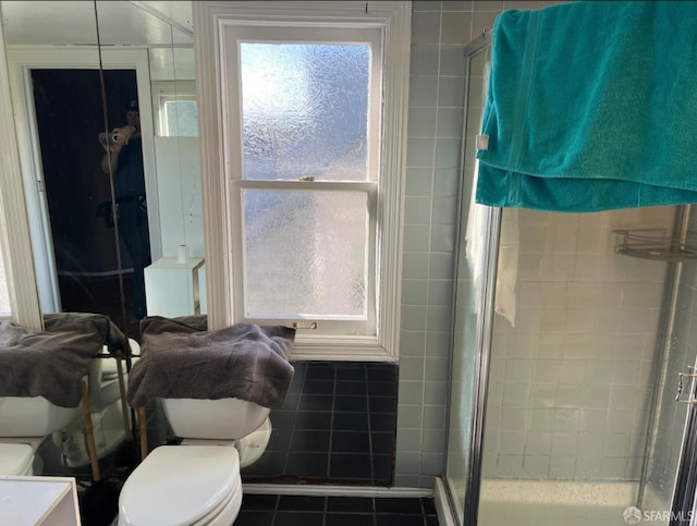 bathroom featuring toilet, an enclosed shower, and tile patterned flooring