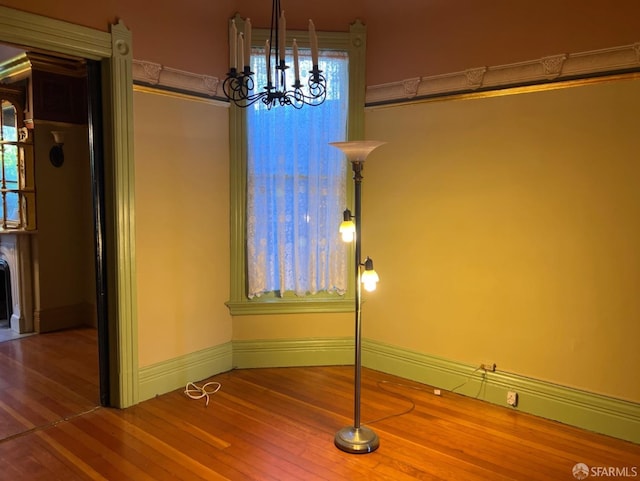 unfurnished dining area with hardwood / wood-style floors and a notable chandelier