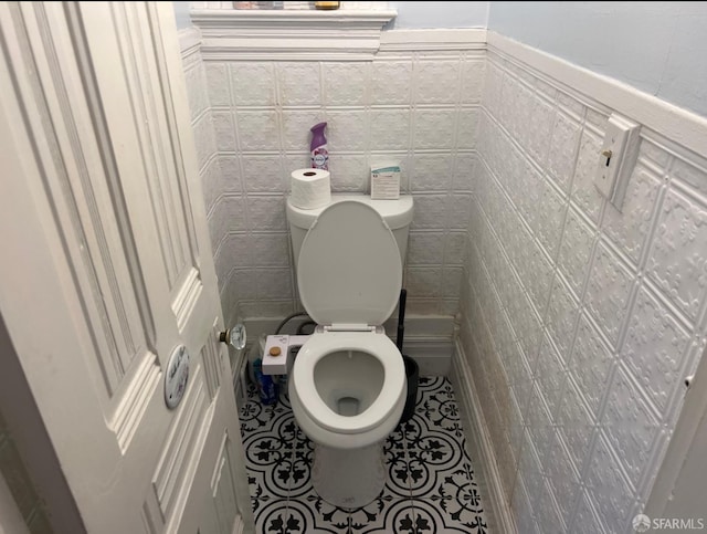 bathroom with tile walls, tile patterned floors, and toilet