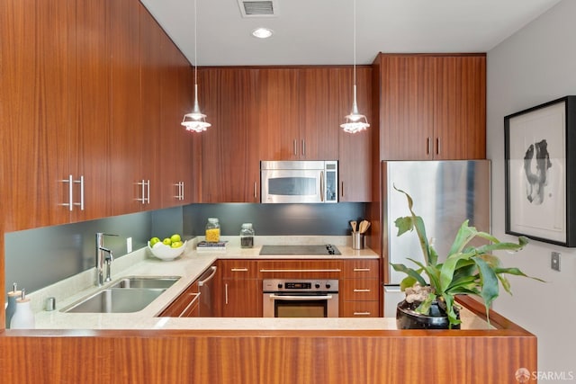 kitchen with stainless steel appliances, hanging light fixtures, sink, and kitchen peninsula