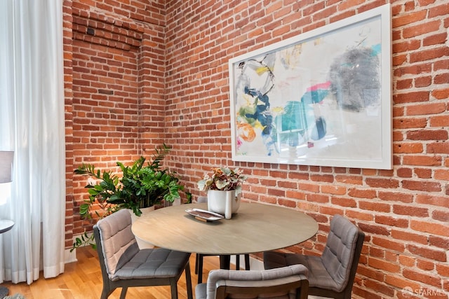 dining room featuring light hardwood / wood-style floors and brick wall