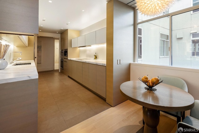 kitchen with stainless steel oven, expansive windows, light stone countertops, and sink