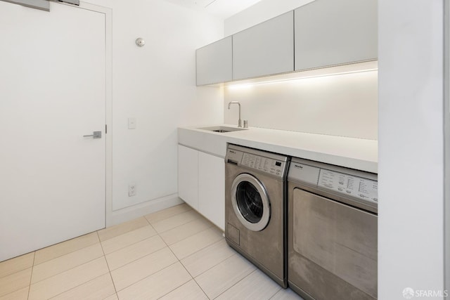 washroom featuring cabinets, light tile patterned flooring, independent washer and dryer, and sink