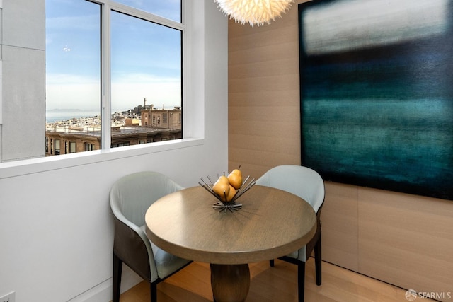 dining space with wood-type flooring, plenty of natural light, and an inviting chandelier