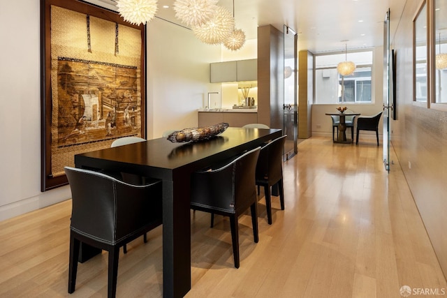 dining space featuring light wood-type flooring and an inviting chandelier