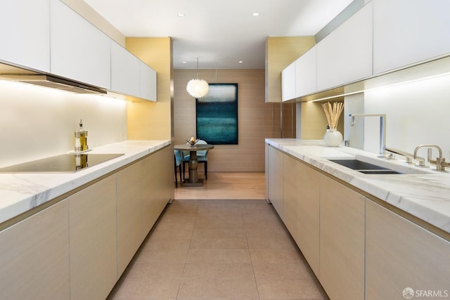 kitchen featuring pendant lighting, sink, light tile patterned flooring, light stone counters, and black electric cooktop