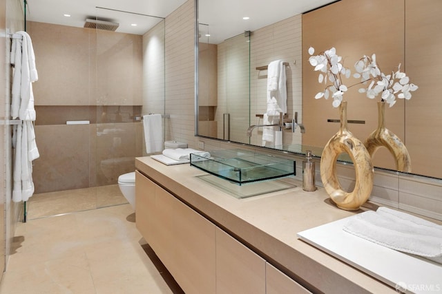 bathroom featuring tile patterned floors, vanity, tile walls, toilet, and walk in shower