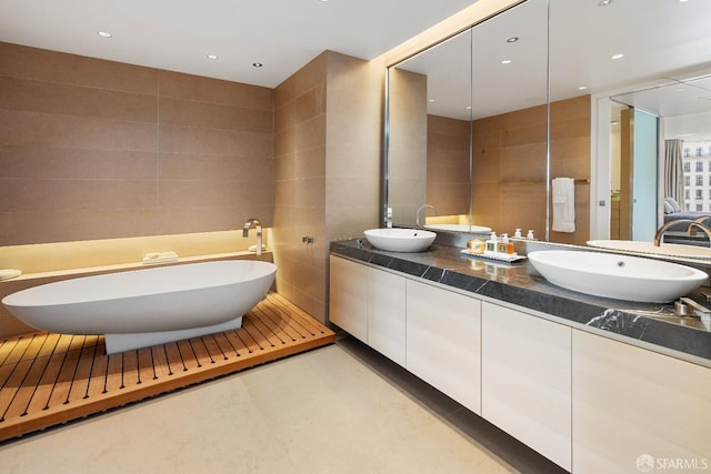 bathroom featuring a bathtub, vanity, and tile walls