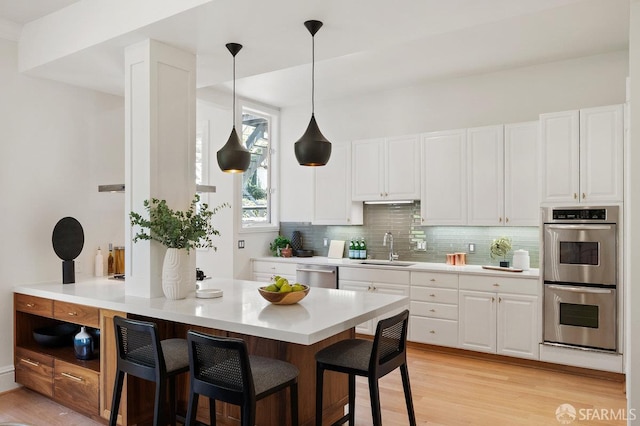 2864 Sacramento St, San Francisco, CA 94115 - kitchen with stainless steel appliances, a sink, a breakfast bar, white cabinets, and light countertops