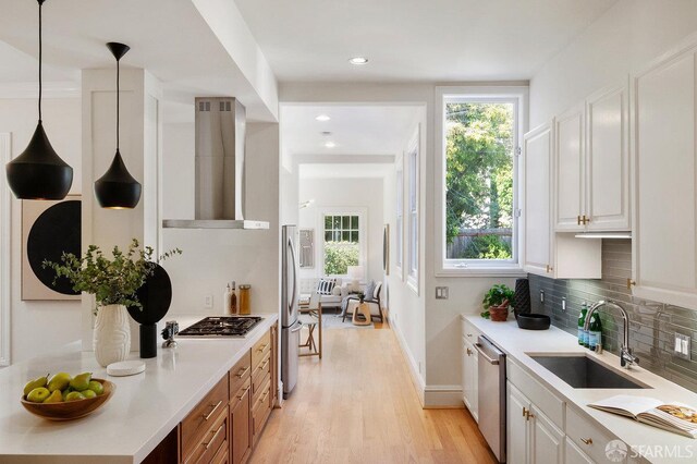 2864 Sacramento St, San Francisco, CA 94115 - kitchen with wall chimney range hood, a sink, stainless steel appliances, light wood-style flooring, and tasteful backsplash