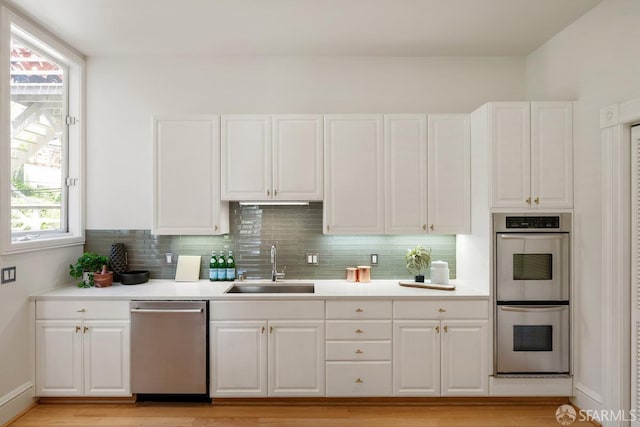 2864 Sacramento St, San Francisco, CA 94115 - kitchen featuring stainless steel appliances, a sink, white cabinetry, and backsplash